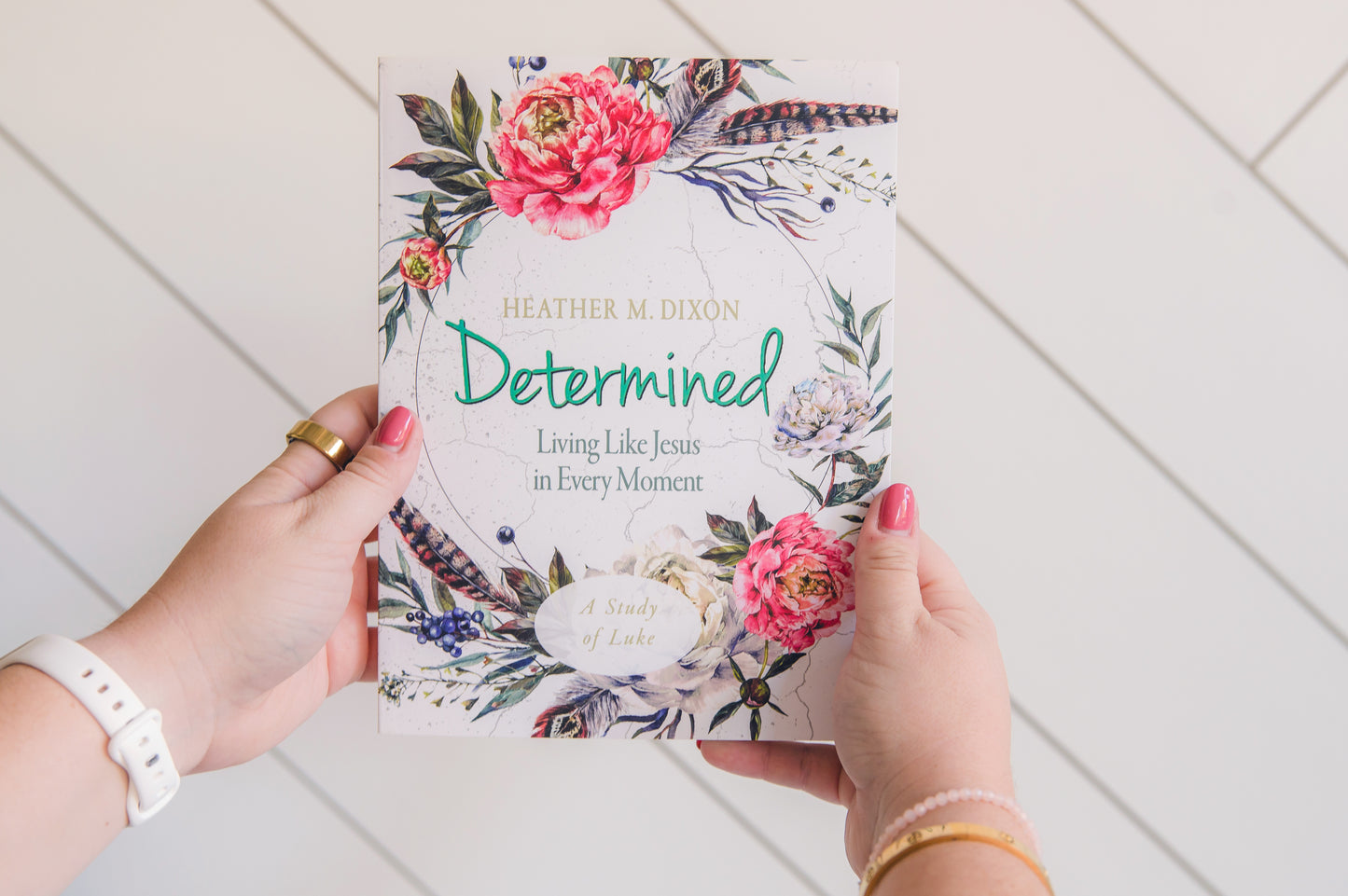 Book titled 'Determined' held by hands on a white wooden surface