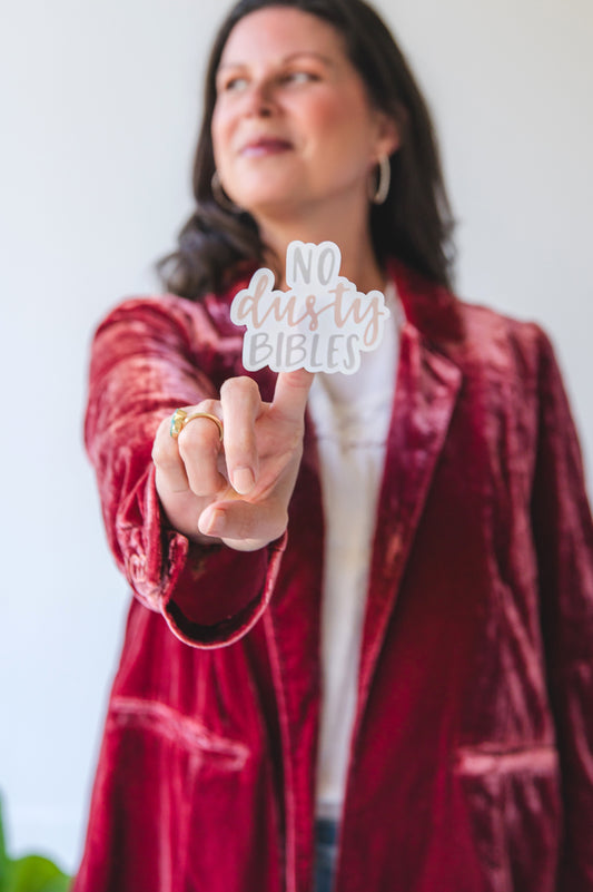 Woman holding a 'No Dusty Bibles' sign in front of a white background