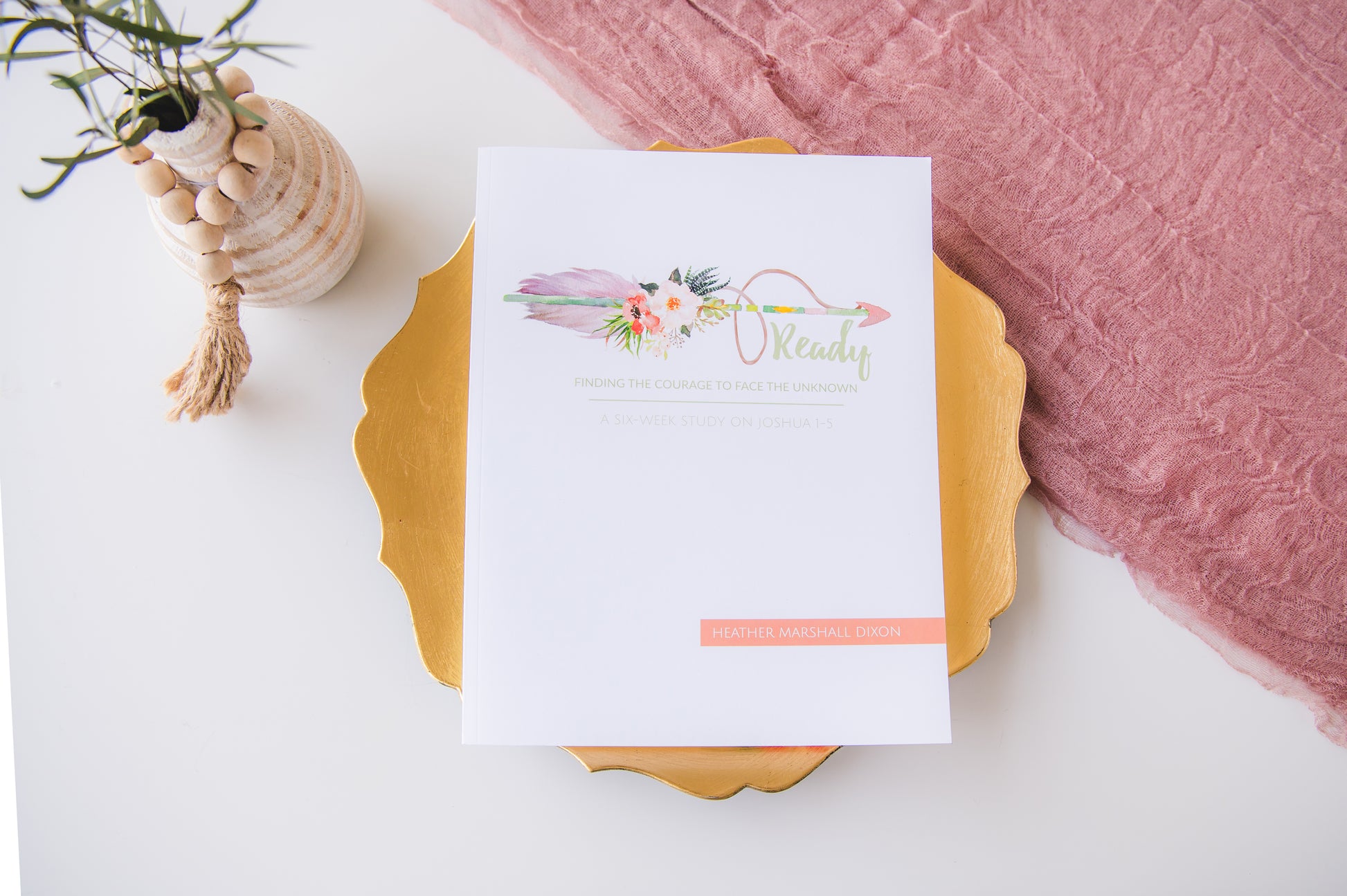 Notebook with floral design on a white surface with pink fabric and shell decoration.